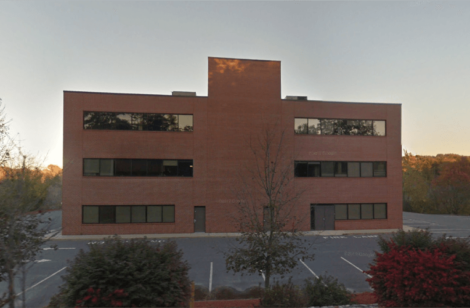 Large brick building with an empty parking lot and sunset in the background.