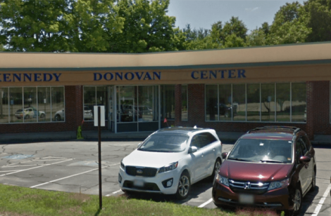 Photo of a building with 3 cars in the parking lot.