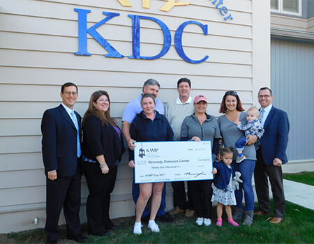 Multiple people posing for a picture and holding up a large check.