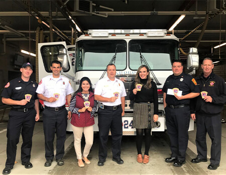 Group of fire fighters standing in front of a truck.