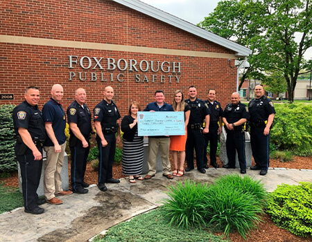 Police officers and citizens holding up a giant check in front of the police department building.