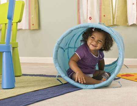 Infant playing in a toy tube.