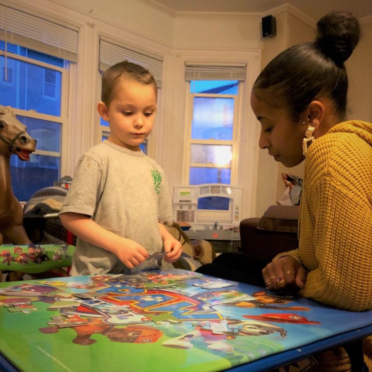 Little boy playing with a puzzle with a caregiver.