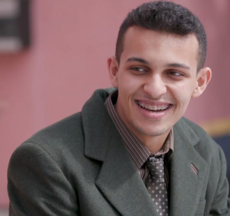 Teenager with braces wearing a suit and smiling